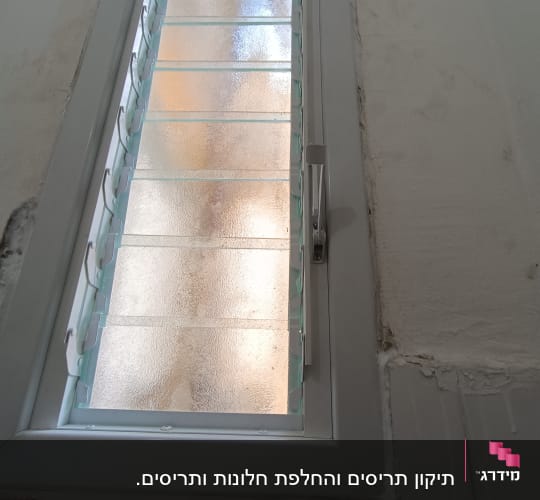 חלון עם תריסים מותקנים על קיר